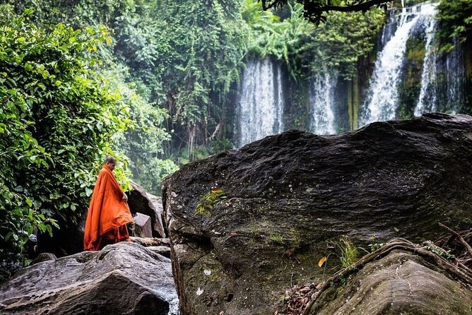 monk standing in front of kulen waterfall